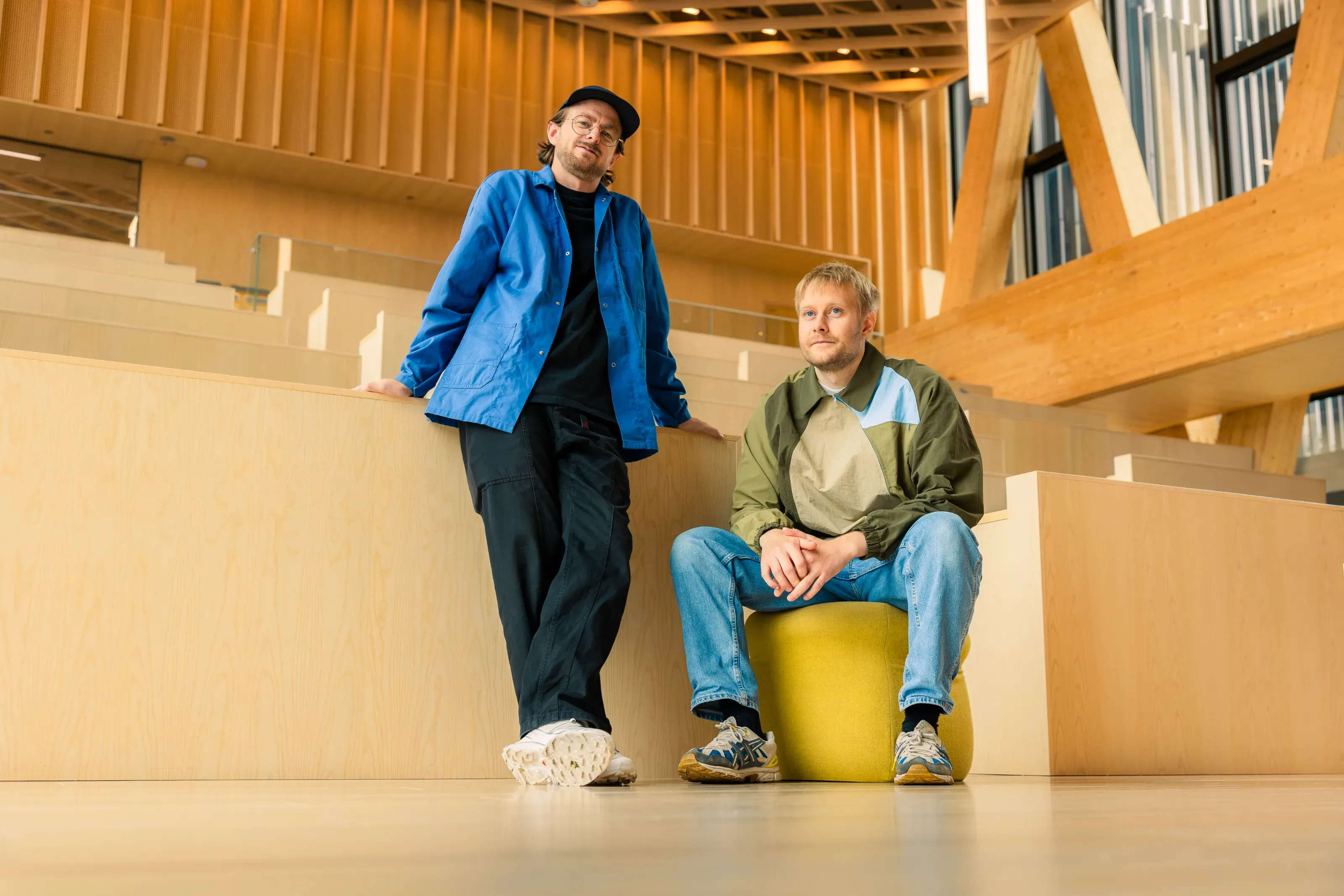 To personer ser ned på fargekart og designmateriell på et bord med keramikkskåler og andre designobjekter.